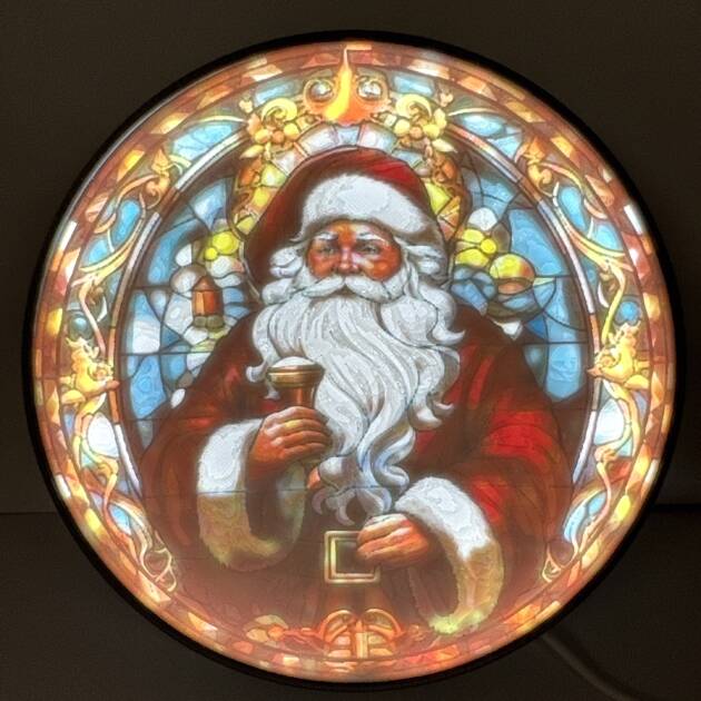 Round colorful Santa decoration lithophane with stained glass style illustration, illuminated from behind.