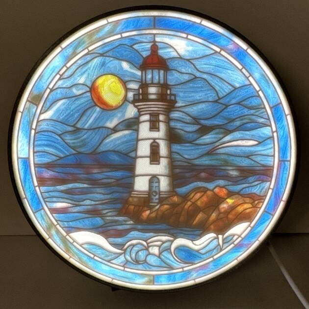 Stained Glass Lighthouse Lithophane of a lighthouse with waves and a sun, set in a circular frame.